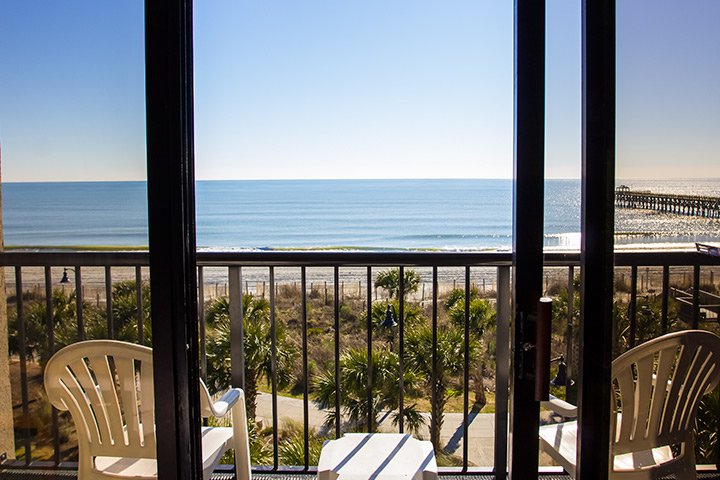 A balcony with a view of the ocean and a pier.